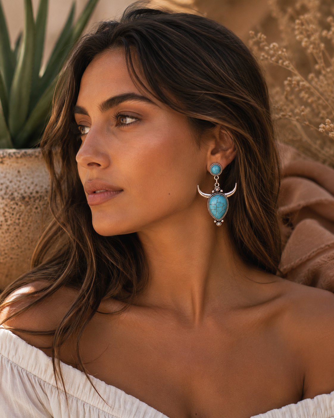 Woman wearing turquoise western earrings in a desert-inspired setting