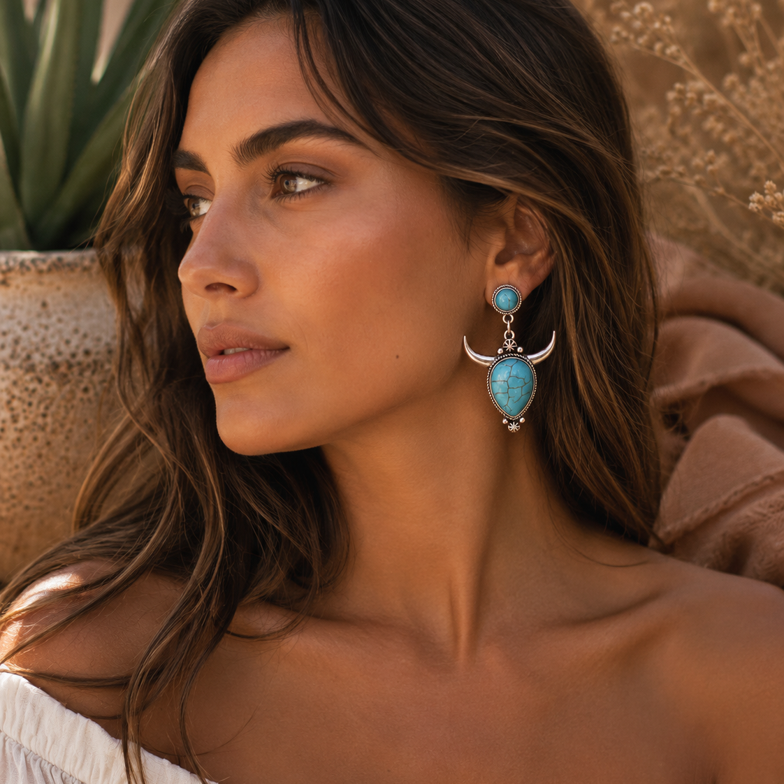 Woman wearing turquoise earrings with a neutral background