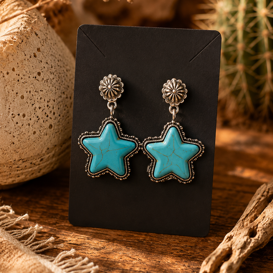 Turquoise star earrings on a black card with natural elements in the background